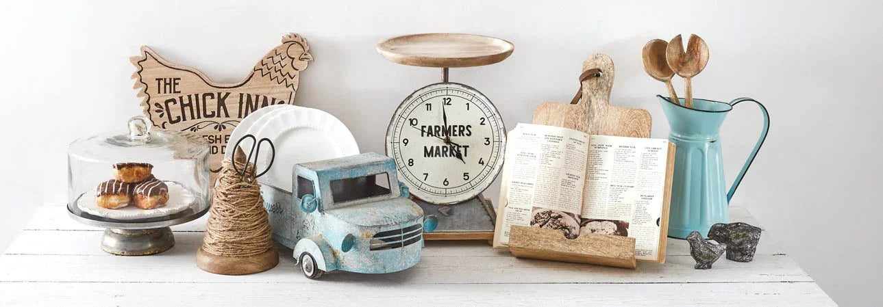 Curated kitchen decor including napkins, aprons, pitchers, and trays styled in a coastal-inspired, layered interior.