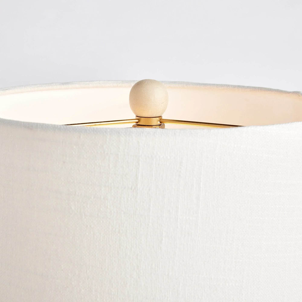This table lamp features a whitewash cane rattan weave and each piece has its own unique color variations. It is a timeless piece complemented by a wide cylindrical shade, perfect for any bedroom, living room, or study. The lamp is handcrafted and features a European-style shade, making it a one-of-a-kind addition to any space.