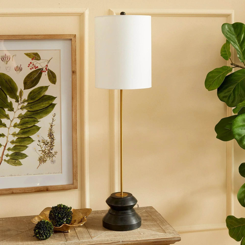 This tall, narrow lamp features a geometric turned wood black wash base, making it ideal for placement on either side of a long console or entry table. With its sleek and straightforward design, it provides a lovely way to illuminate a room with its soft light and black and gold accents, complemented by a linen shade.