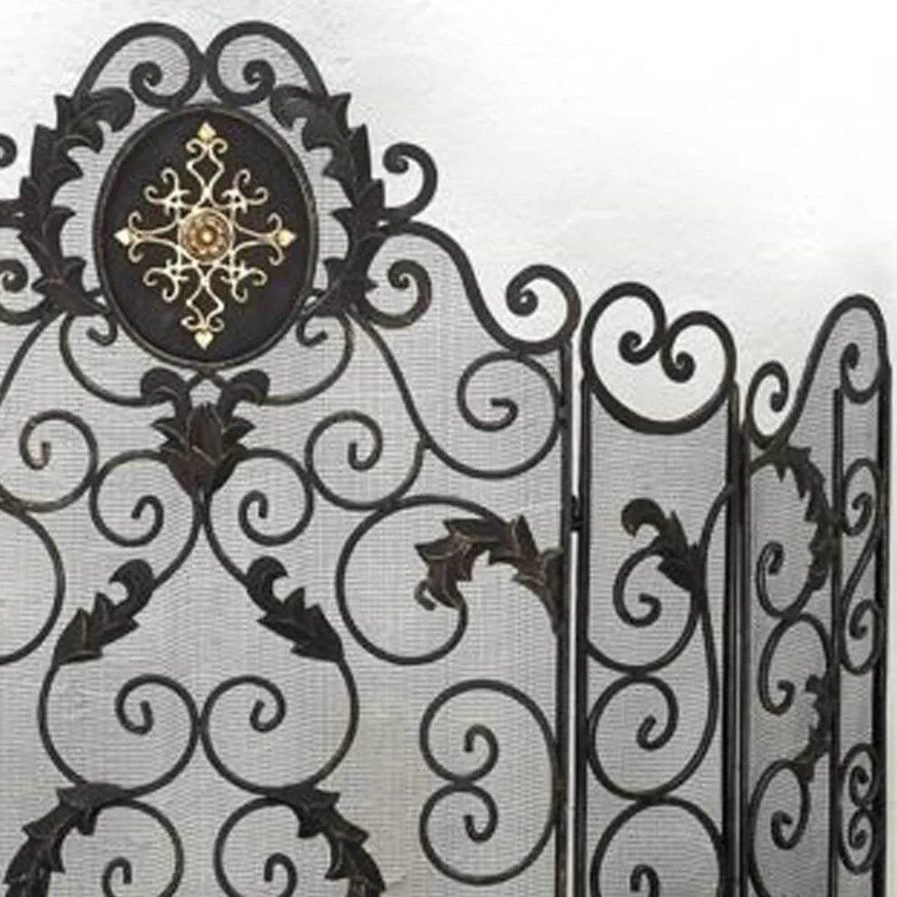 Angled view of handcrafted wrought iron fireplace screen featuring curved five-panel structure, mesh backing, and scroll detailing in a dark finish.