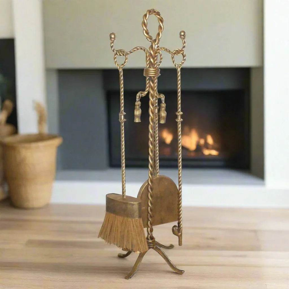 Side view of hand-forged fireplace tools in antique gold finish, showing twisted iron handles and decorative tassel accents.