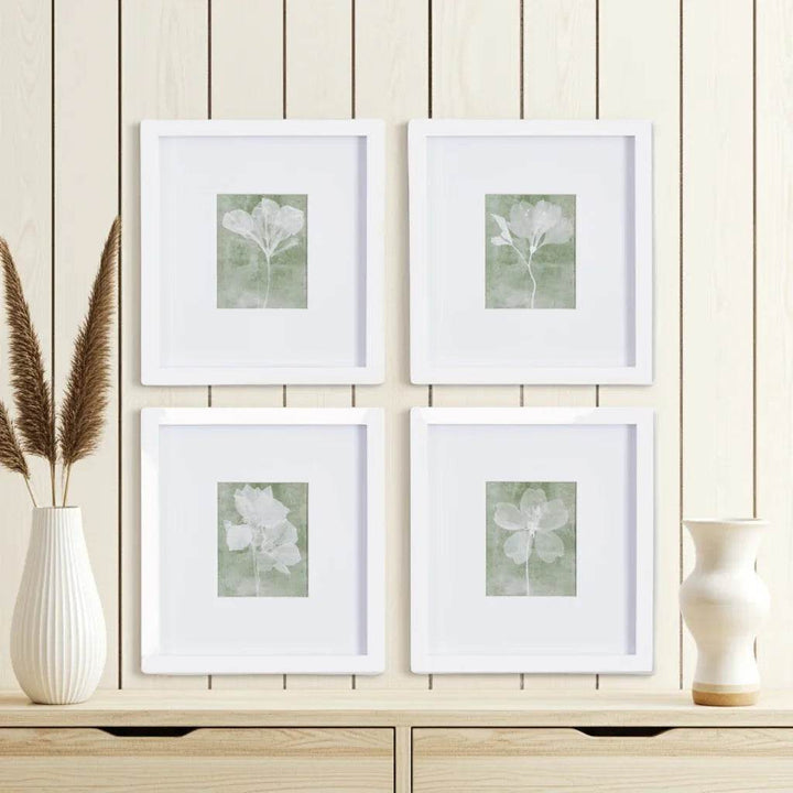 Close-up of framed green floral prints with white mats styled against neutral wood paneling