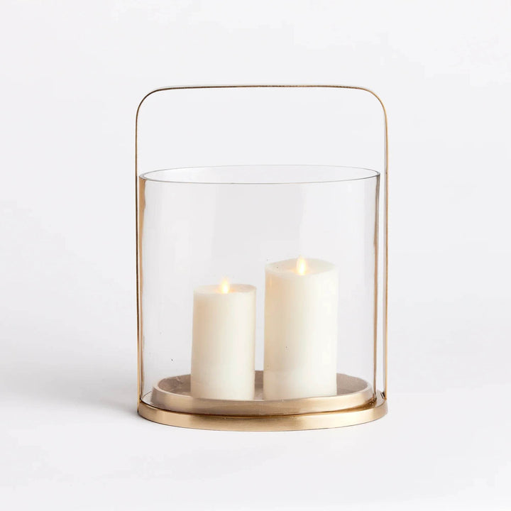 Front view of large oval brass and glass hurricane candle holder with two LED pillar candles inside