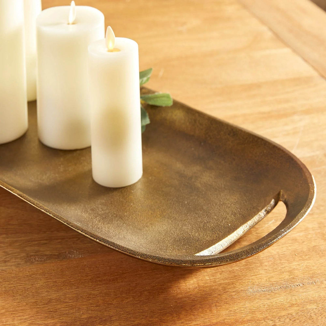 Brass tray with pillar candles and greenery on a wood surface for styling inspiration – Transitional