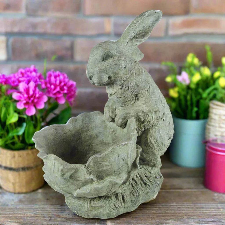 Cement bunny planter with textured detail displayed on rustic wood surface with pink and yellow spring flowers