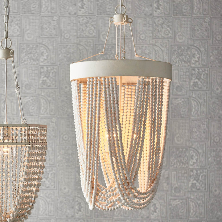 White wood bead pendant light illuminated and styled in interior setting with patterned wall backdrop – Coastal Boho