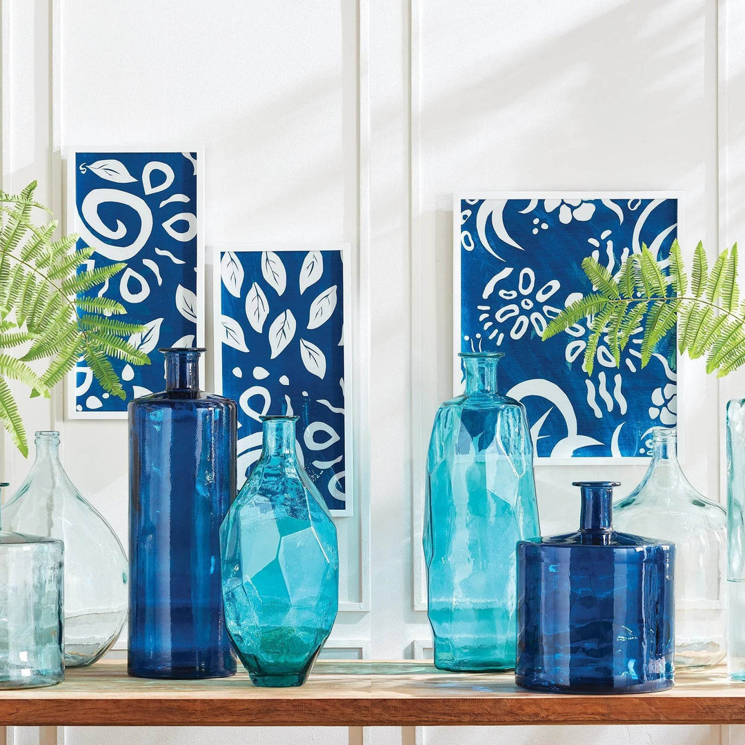 Abstract blue and white wall prints styled with sea glass vases, highlighting modern coastal color harmony.