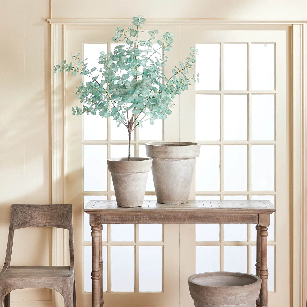 Faux eucalyptus drop-in styled in terra cotta pot on console in minimalist entryway