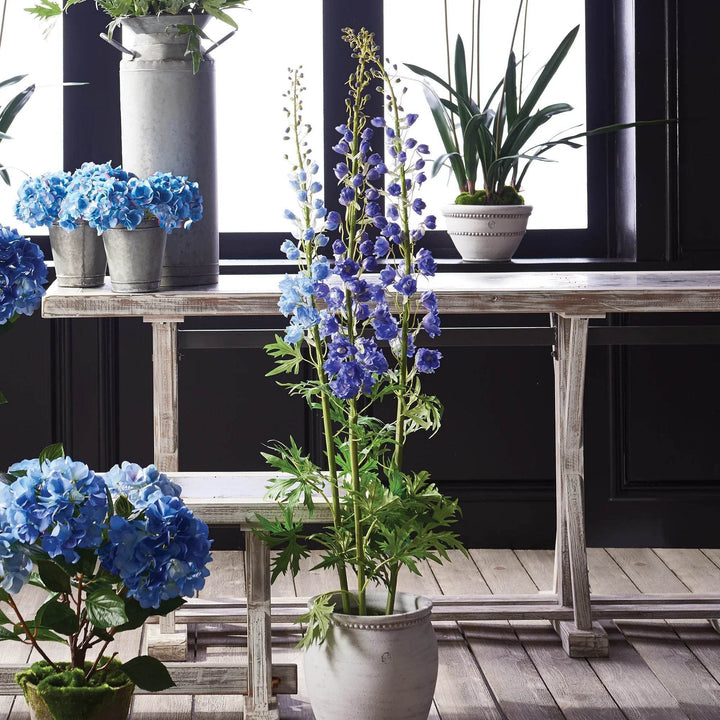 Faux delphinium stem styled in a white ceramic planter with blue florals on rustic wood bench – Modern Cottage