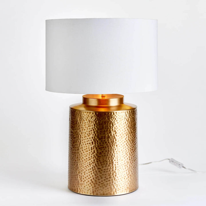 Studio shot of hammered brass table lamp with white gallery shade