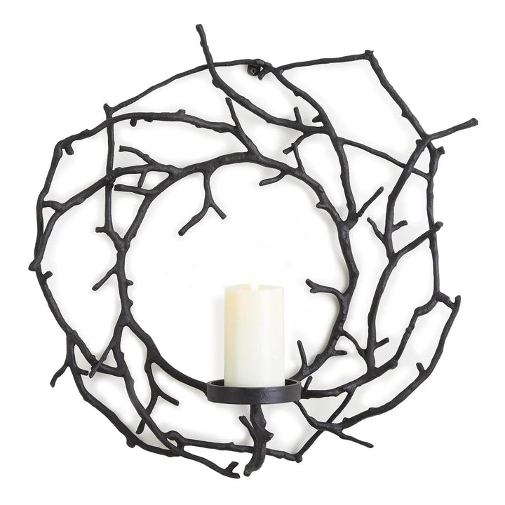 Wall-mounted black branch-style candle holder in a clean minimalist room setting with soft lighting.