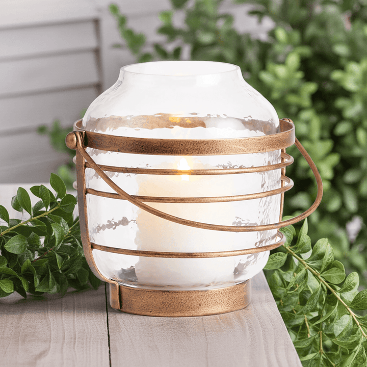 Hammered glass hurricane with antique gold iron banding, styled outdoors on stone surface with pillar candle – Coastal