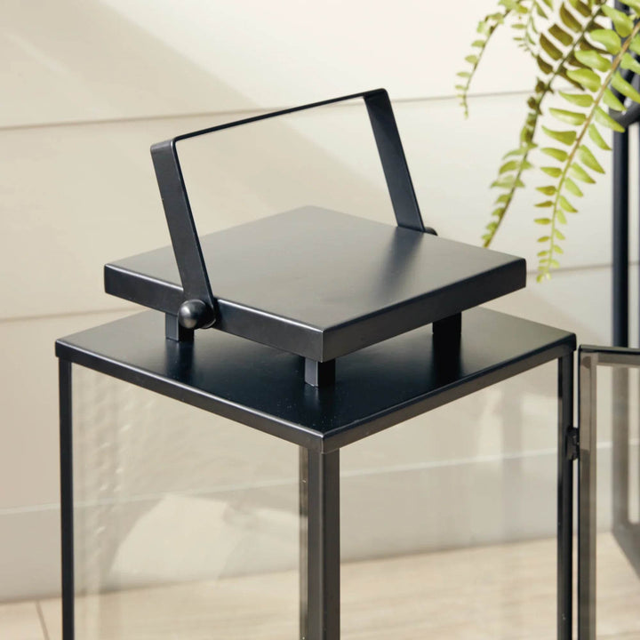 Detail of small black stainless steel outdoor lantern handle and square top design with clean architectural lines – Transitional