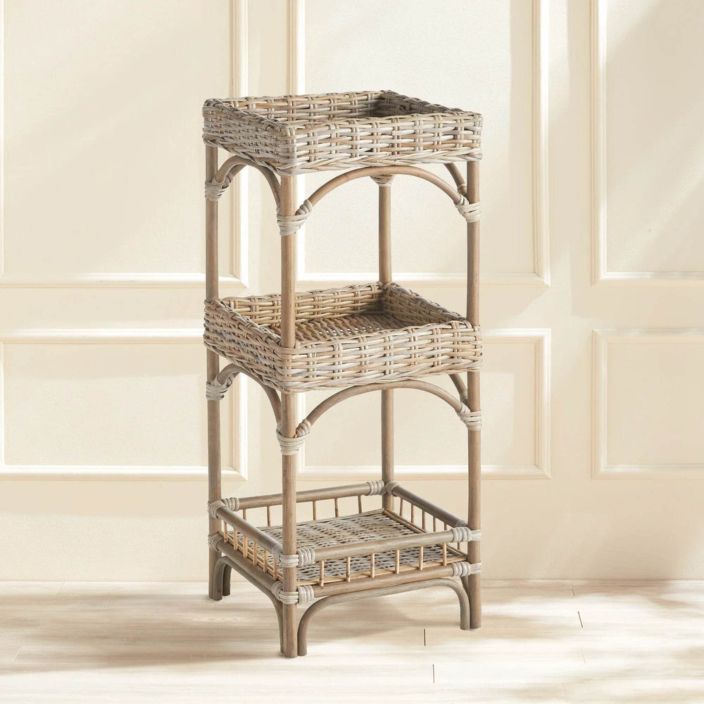 Woven rattan tiered shelf styled in a neutral room with paneling, showing its coastal boho utility.