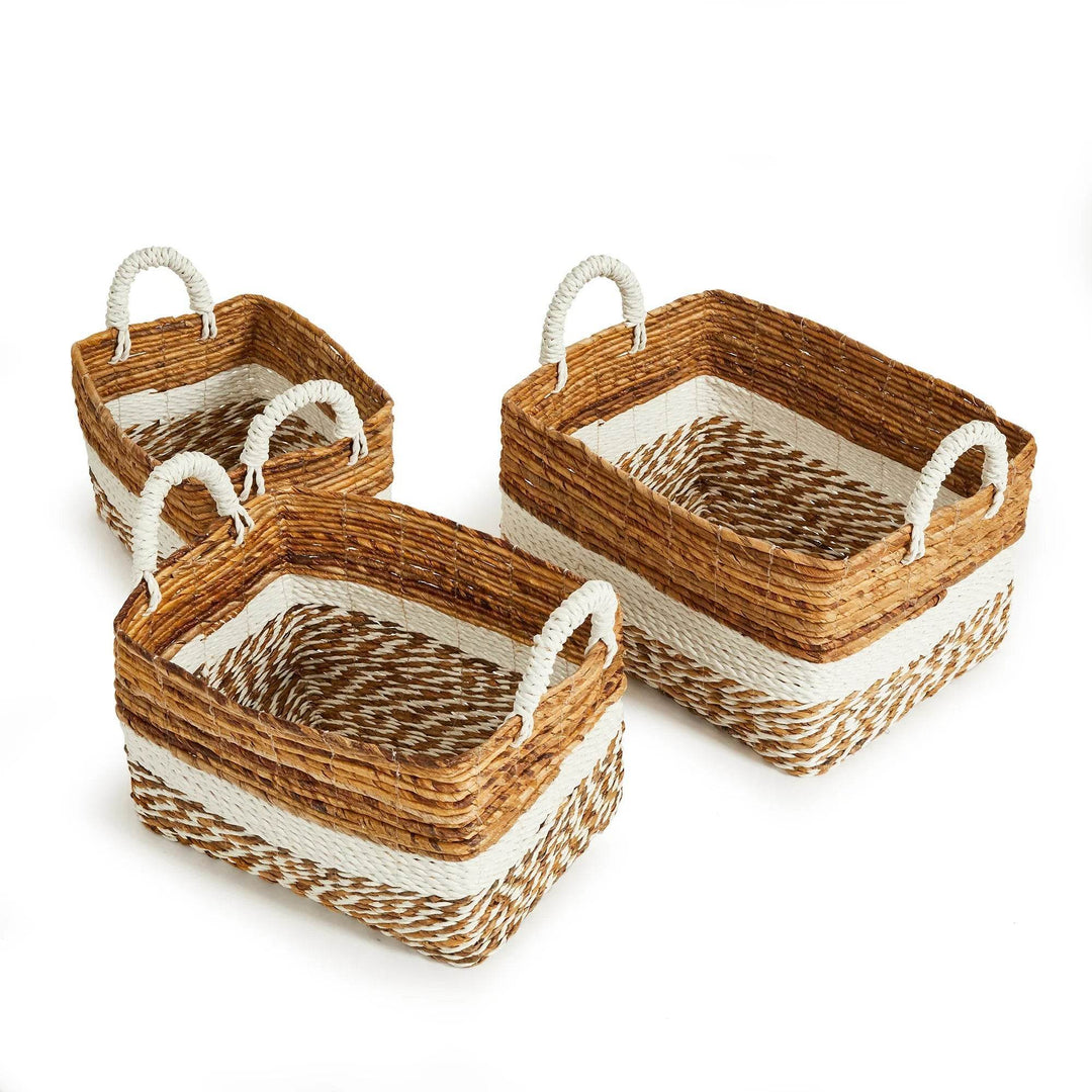 Three decorative baskets in warm natural fibers and white bands, styled on coastal flooring – Boho Natural