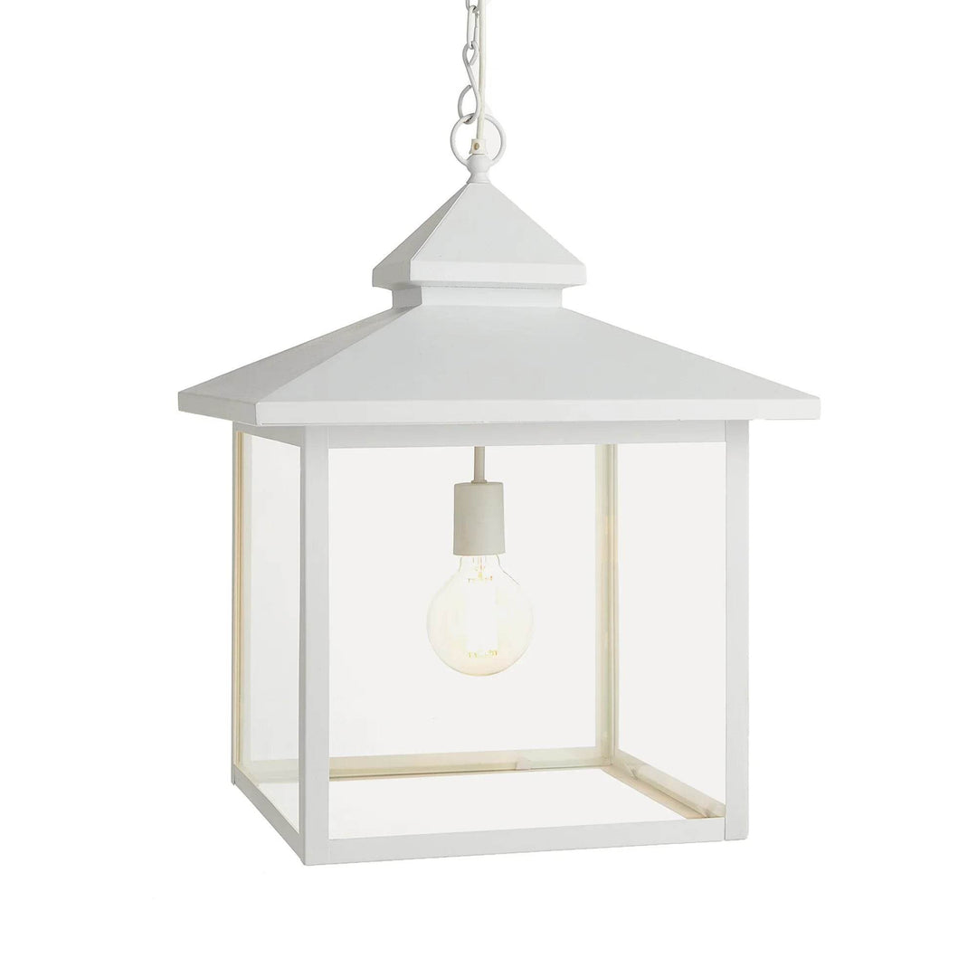 Refined farmhouse white pendant light with barn-style roofline and glass panels, front view.