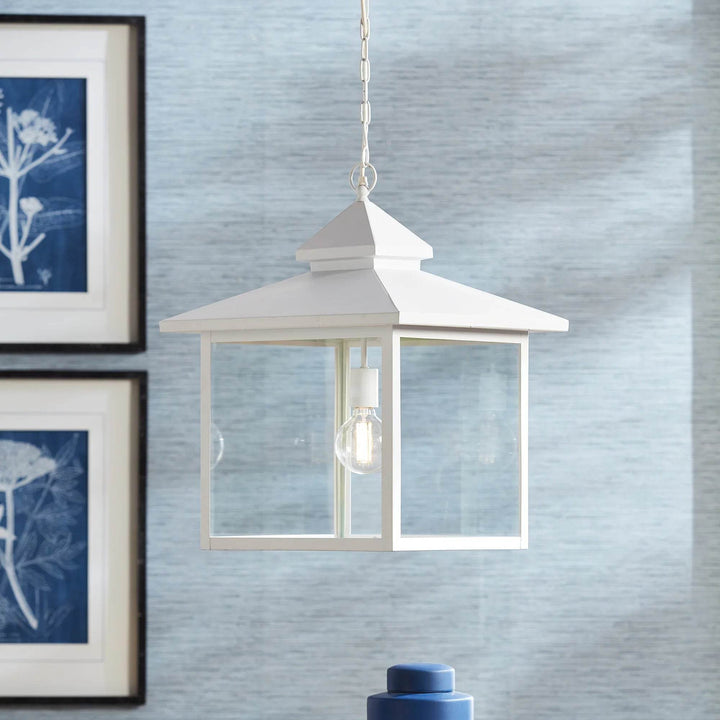 Refined farmhouse pendant light shown in a modern space with blue wall and framed prints.