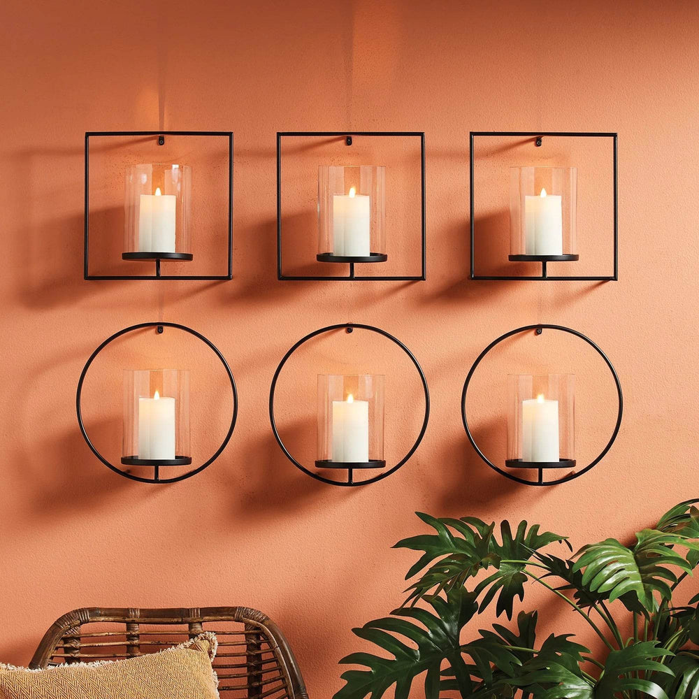 Set of round and square black wall candleholders styled in a grid on a terracotta wall, each holding a glowing LED candle – Industrial Modern.