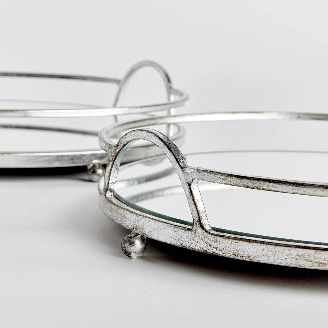 Angle detail of round mirrored trays showing antique silver finish and mirrored glass surface, modern classic styling
