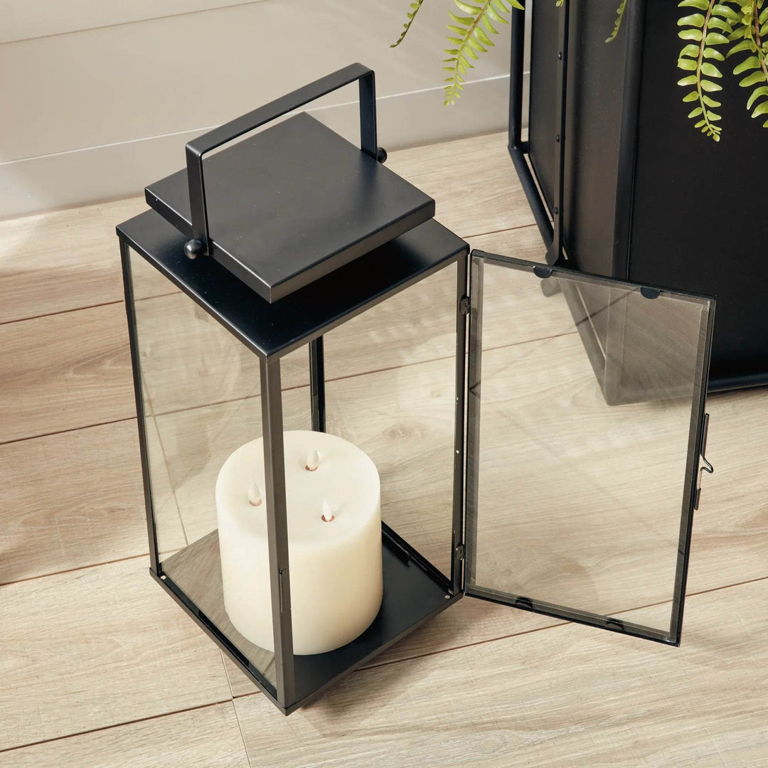 Small black stainless steel outdoor lantern with hinged glass door open, showing pillar candle placement – Transitional