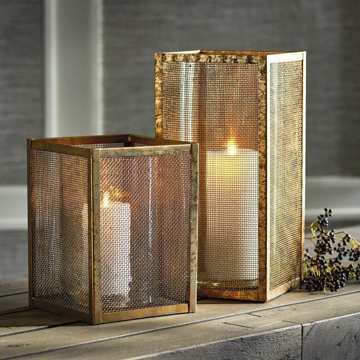 Pair of gold mesh hurricane candle holders, 10 inch and 15 inch, styled on table with lit candles for modern industrial decor.