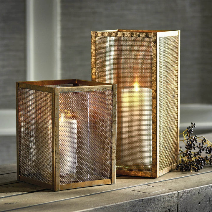 Pair of gold mesh hurricane candle holders, 10 inch and 15 inch, styled on table with lit candles for modern industrial decor.