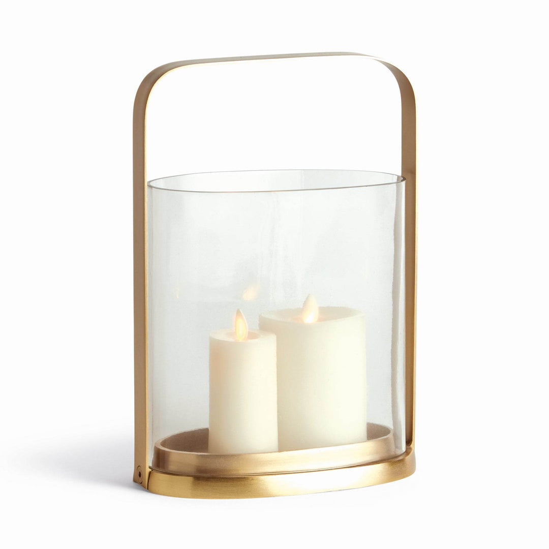 Transitional small brass and glass hurricane candle holder with two white candles inside, front angled view.
