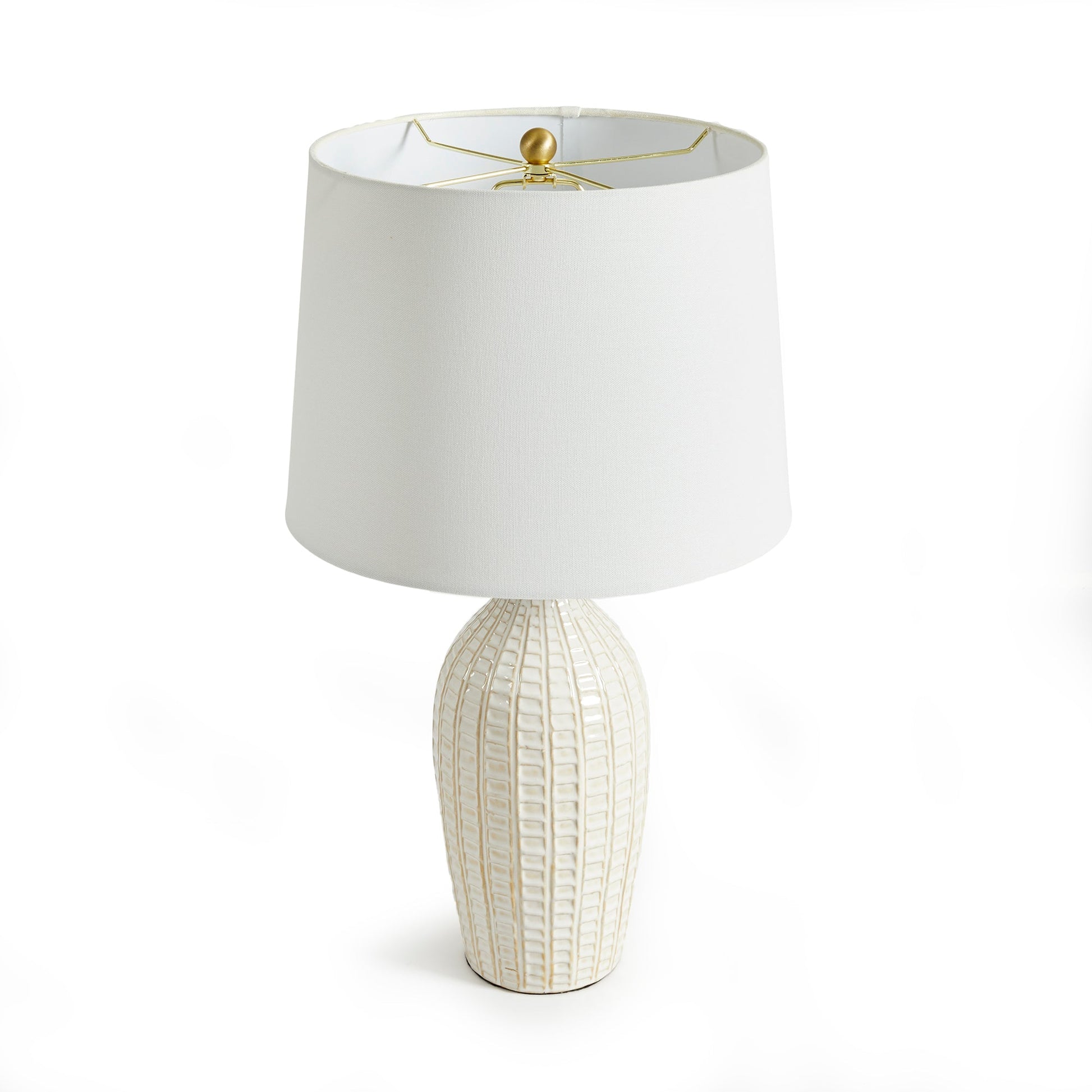 With a pressed pattern on the ceramic body, the Nadia Lamp is a work of art. Topped off with a generously scaled fabric shade, it is sure to enhance any space. intricate details, bold, finial, classic white, metal accents This ceramic lamp boasts an eye-catching pressed pattern and an elegantly designed fabric shade, making it an artistic addition to any room. With intricate details, a bold finial, and classic white coloring with metal accents, it offers both style and subtlety.