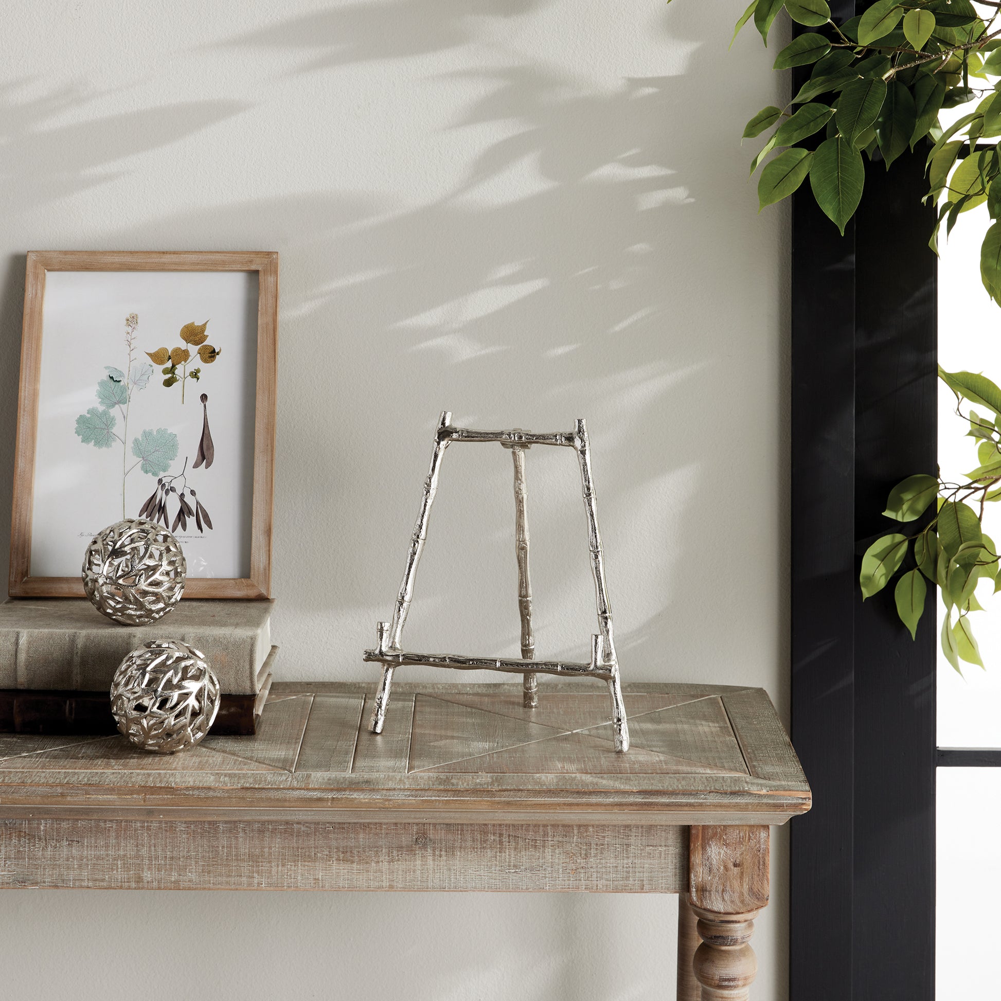 Elevate your decor with this sturdy and resilient silver easel, expertly crafted to exhibit platters, cookbooks, or small art pieces. The traditional aesthetic of bamboo-like silver details adds a timeless charm, while the versatile design allows for effortless display of various items.