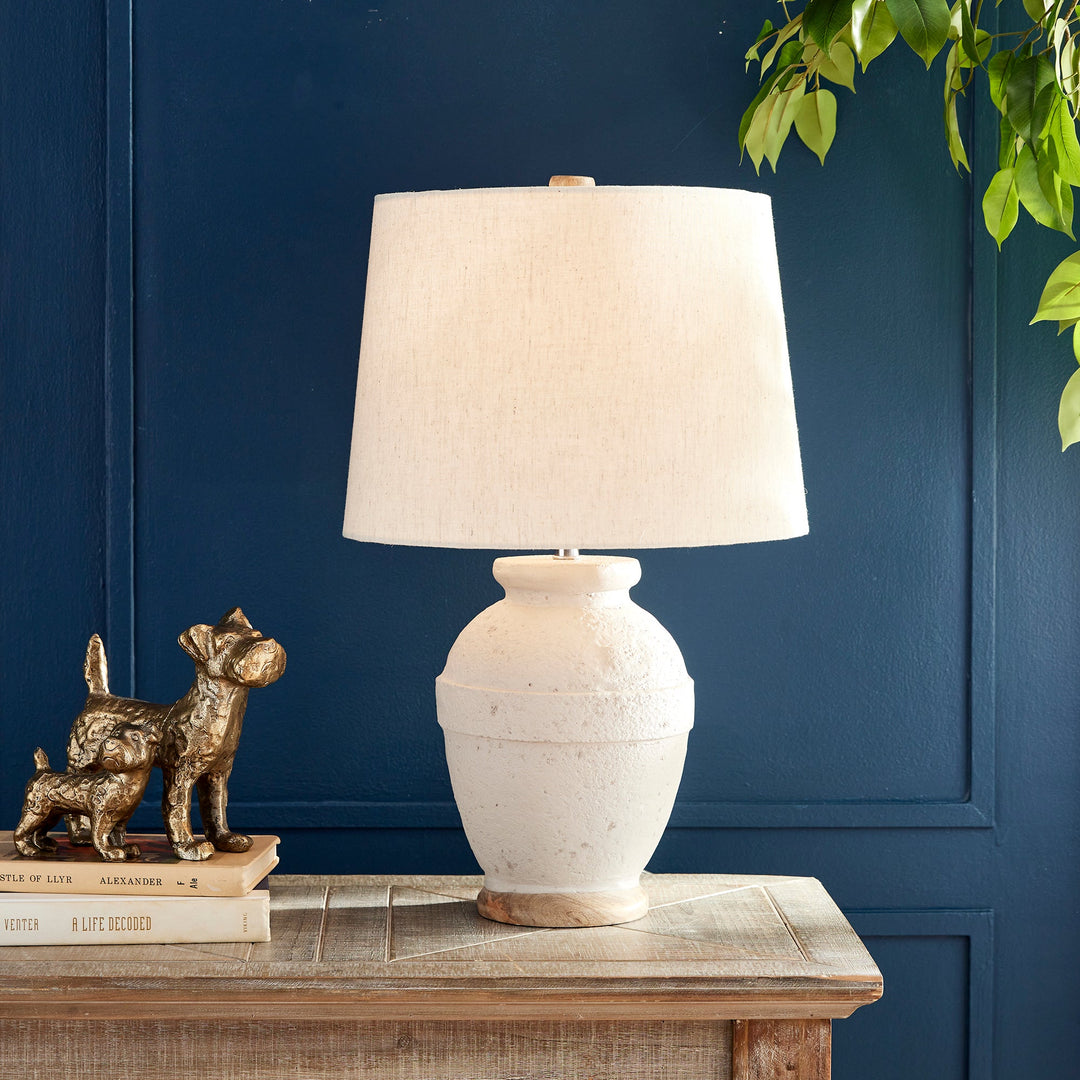 This table lamp features a composite base made of natural Eco mix, incorporating hardening agents for long-lasting durability. The warm white finish adds a subtle texture, showcasing the unique composition of the material. Topped with a linen tapered shade and banded silhouette, this petite lamp is perfect for bedside tables or desks. Designed with sustainability in mind, it utilizes an Eco mix made from natural materials, combining durability with eco-friendliness.