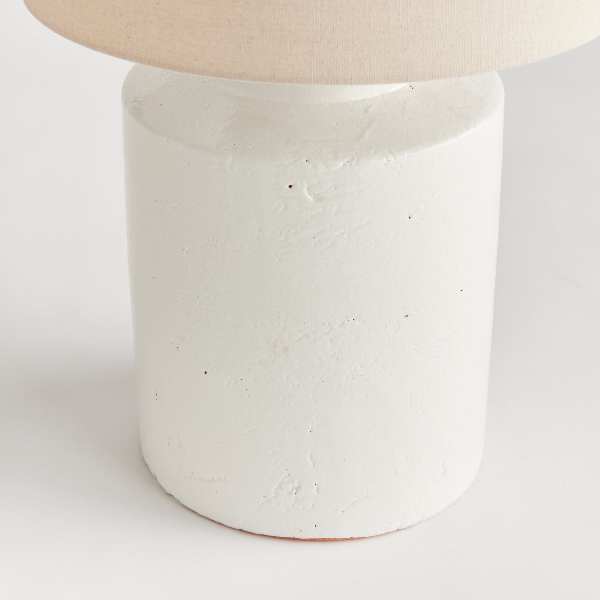 This Monty White Transitional Table Lamp is crafted from elegant white ceramic with a thick glaze, making it a perfect addition to transitional décor. Its generously-sized white linen shade and sleek finial add a touch of sophistication to its timeless design. The table lamp's construction is elegant and durable, creating a lasting beauty that will elevate any space. Add character and style to any room with this versatile and sophisticated lamp.