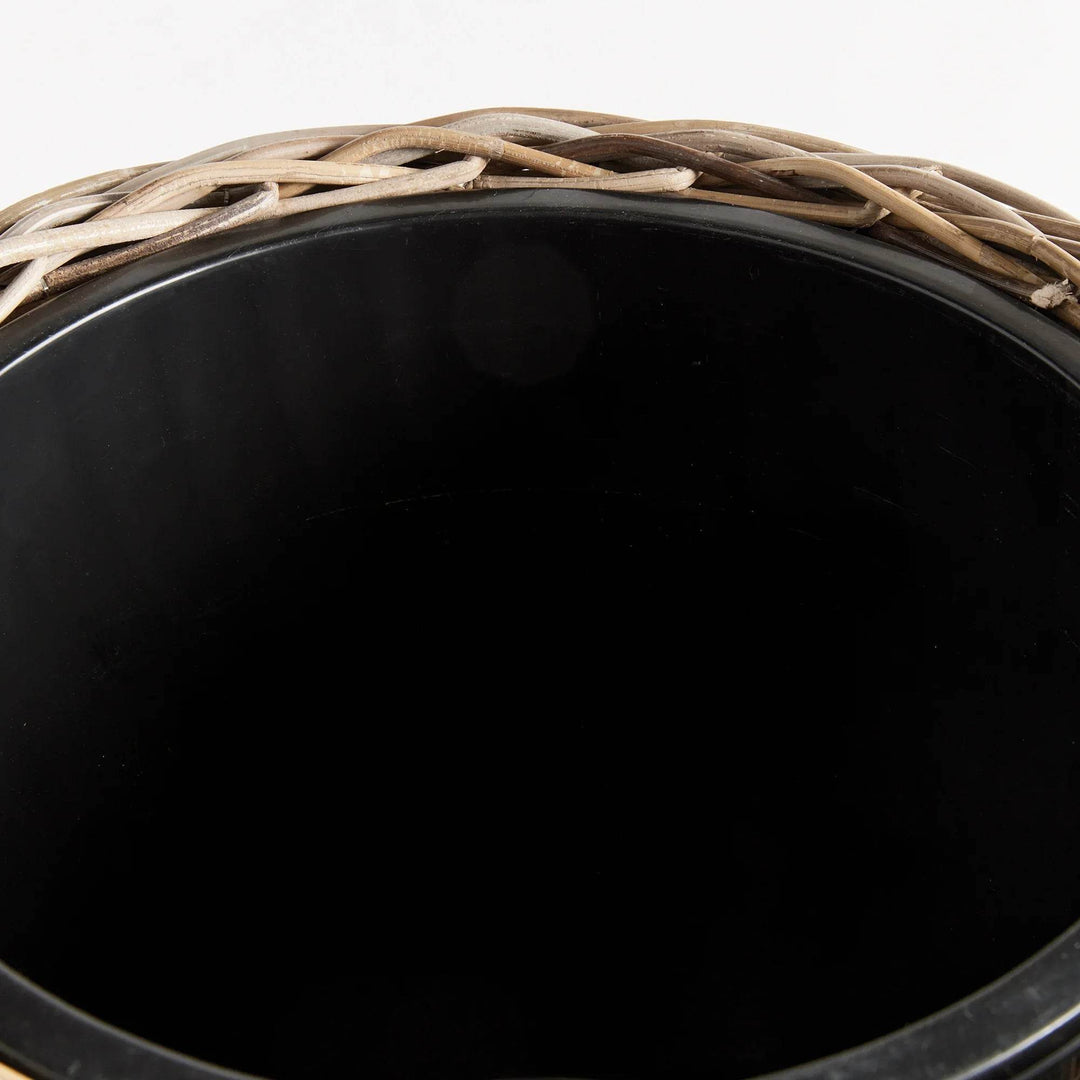 Crafted with all-natural materials, this rattan planter boasts a distinctive flattened weave design and is complemented by a sturdy iron frame and included grower's pot. Perfect for those seeking a durable and aesthetically pleasing option.