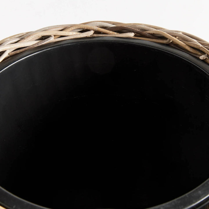 Crafted with all-natural materials, this rattan planter boasts a distinctive flattened weave design and is complemented by a sturdy iron frame and included grower's pot. Perfect for those seeking a durable and aesthetically pleasing option.