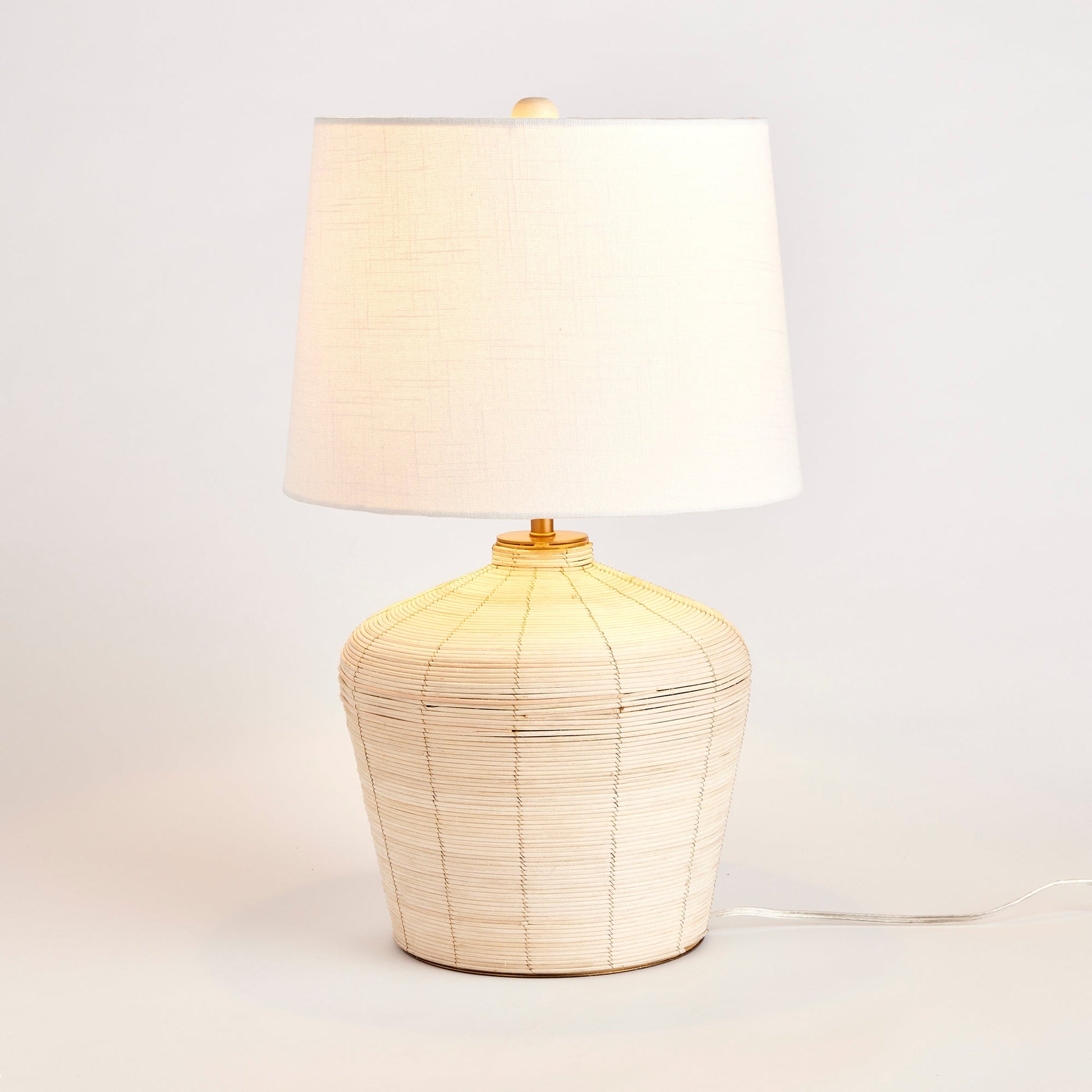 Expertly handcrafted with a distinctive whitewash cane rattan weave, the Maye Tapered Rattan Table Lamp is truly one-of-a-kind. Its wide cylindrical shade makes it a versatile and charming accent for any bedroom, living room, or study. With unique color variations achieved through the weaving process, this lamp adds a touch of elegance to any room. Complete with a matching finial, it is the perfect addition to your home decor.