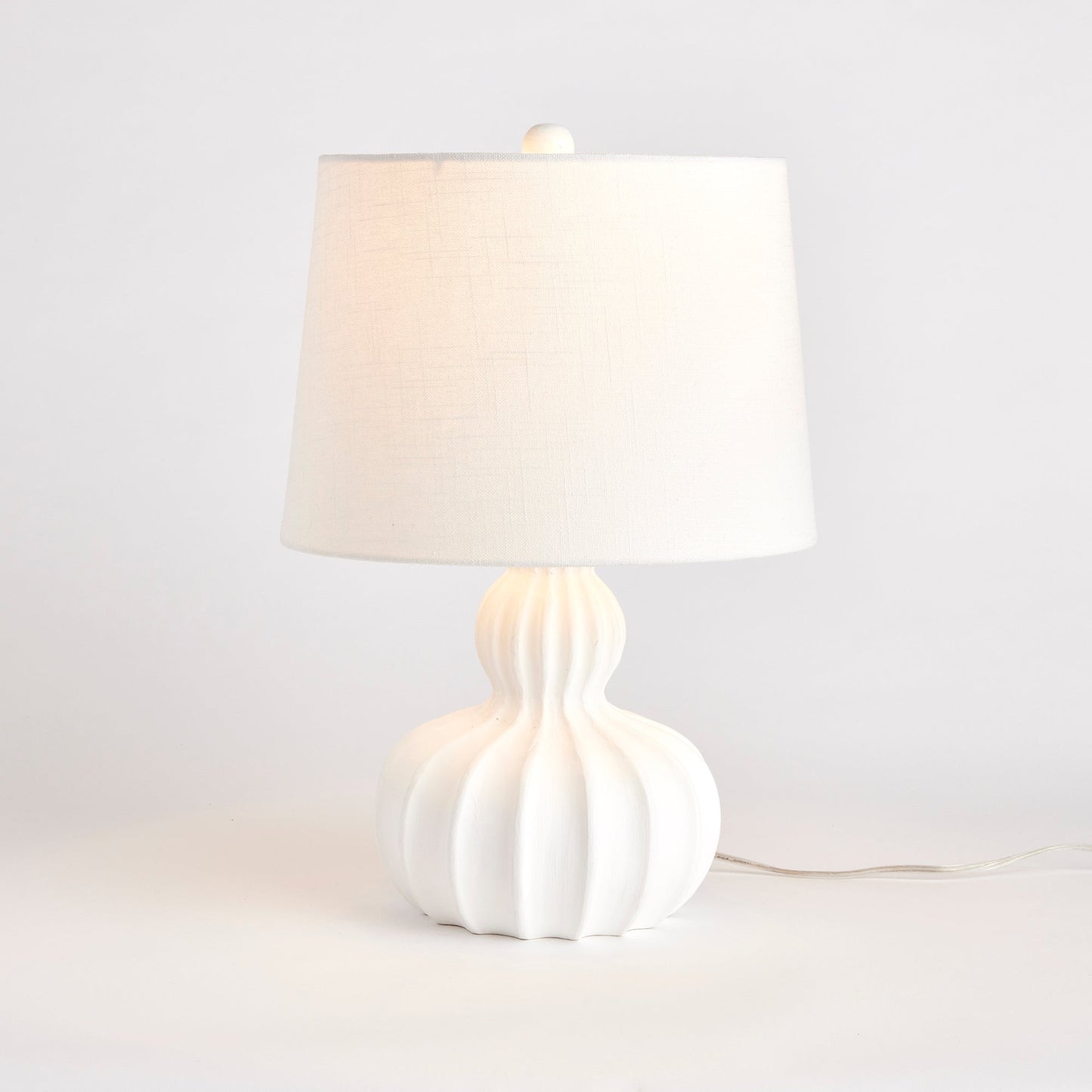 Exquisitely crafted with precision and care, this stunning lamp features a solid carved wood base that adds a touch of elegance to any space. Its unique, curvy sweeping design and large size make it the perfect centerpiece for transitional spaces, while the solid mango wood base and white jute/cotton blend shade offer a touch of natural beauty. Finished with a sleek finial, this lamp is truly one-of-a-kind.