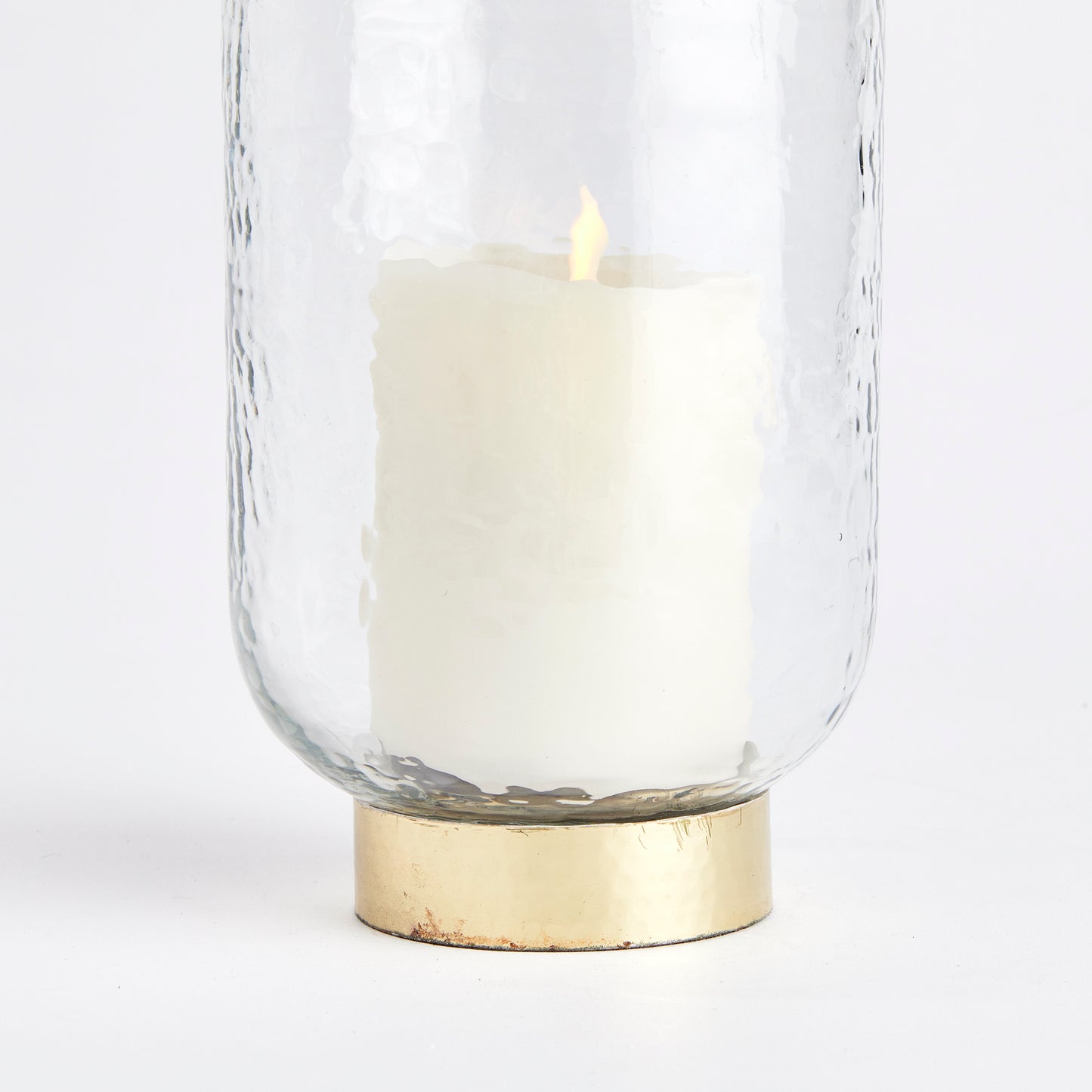 Featuring a thick, hammered glass and a unique melted uneven edge, the Amira Gold Hurricane Medium Candle Holder adds an artisanal touch to any space. Its finishing touch is the elegant hammered gold rim base, making it a sophisticated accent for console, bookshelf, or mantel. Crafted with expert skill, this hurricane is a true testament to fine craftsmanship.