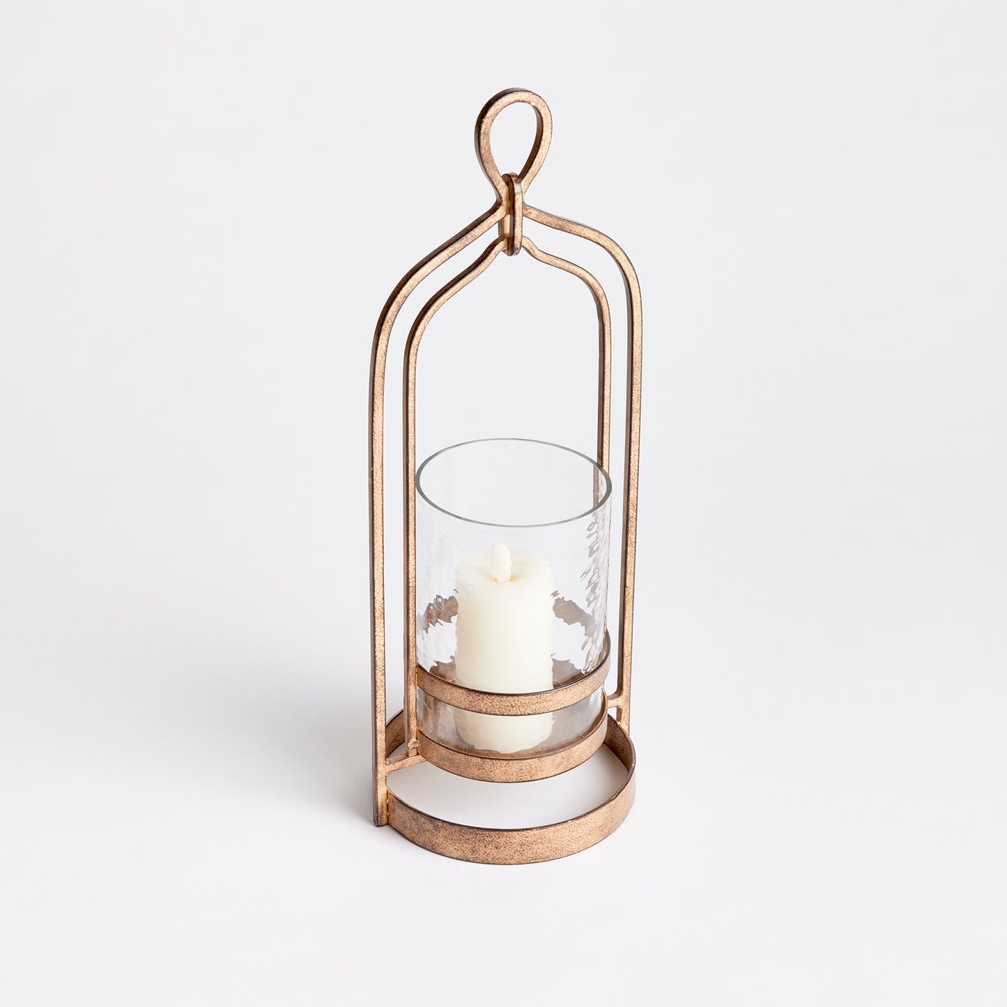 Crafted with precision from sturdy cast aluminum and adorned with exquisite hammered glass, the Amara Gold Hurricane Candle Holder Small showcases a perfect balance of lyrical form and substantial design. A decorative yet functional loop handle completes the look, making it a versatile addition to any transitional or modern setting.