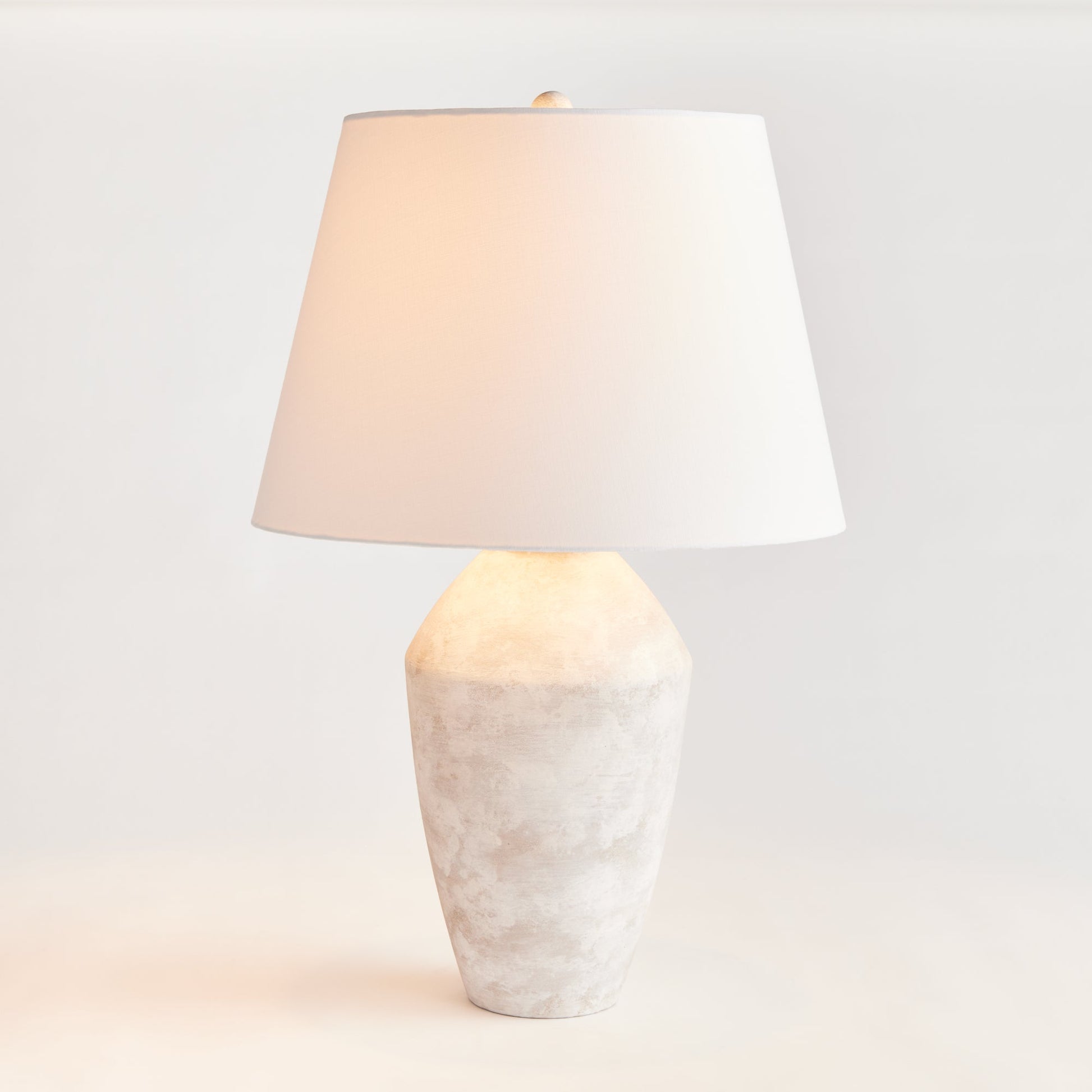 Expertly crafted from a centuries old wooden mold, this warm stone finish table lamp boasts a classic silhouette that will elevate any room. The tapered fabric shade adds a touch of elegance and creates a dynamic, storied lighting experience for any space in your home. Designed for family rooms, studies, and bedrooms, this lamp perfectly balances style and functionality