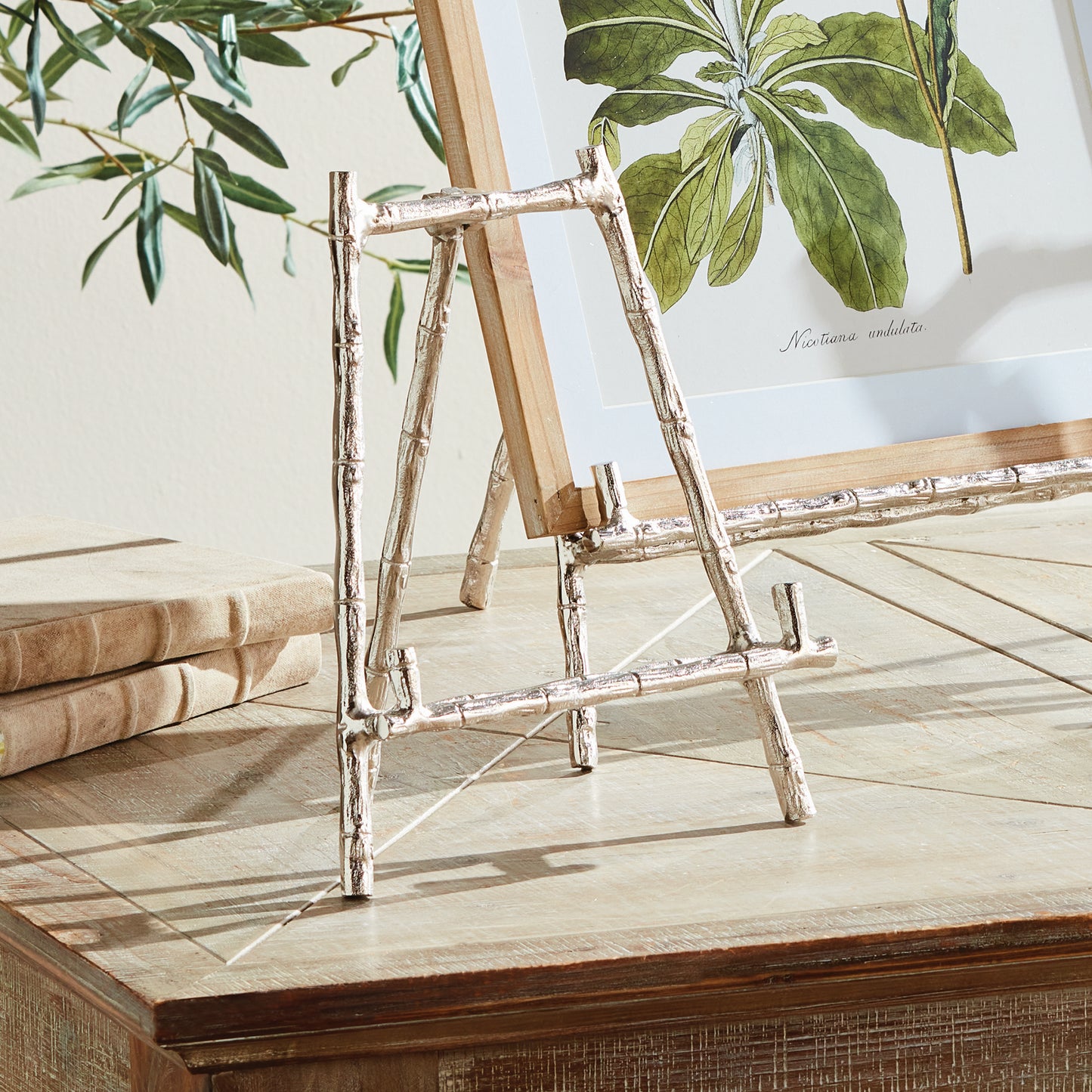 Elevate your decor with this sturdy and resilient silver easel, expertly crafted to exhibit platters, cookbooks, or small art pieces. The traditional aesthetic of bamboo-like silver details adds a timeless charm, while the versatile design allows for effortless display of various items.