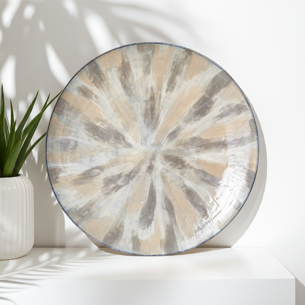 36 inch enameled iron round wall plate with hand-painted cream and taupe brushwork on white studio backdrop – Transitional