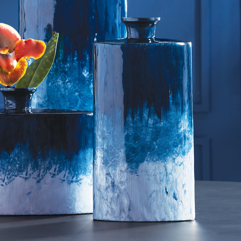 Hand-painted using enameled iron, the Blue Oval Vase Small boasts an elegantly elongated and lightweight design. Its stunning ombre finish, inspired by the beauty of nature and expertly crafted from enameled iron, adds a touch of simple sophistication to any room.