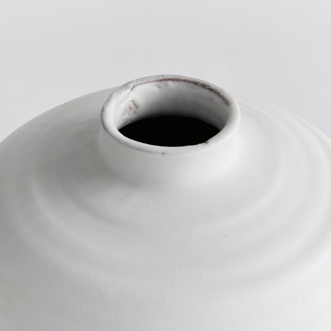 Enhance your decor with the Andorra White Pot Vase. Featuring a unique ribbed design and a smooth, matte white glaze, this vase adds a touch of elegance to any room. Use faux stems or leave it as is for a cleaner look. With its soft subtle ribbing, it brings in a light and neutral accent, making it a must-have for any decor.