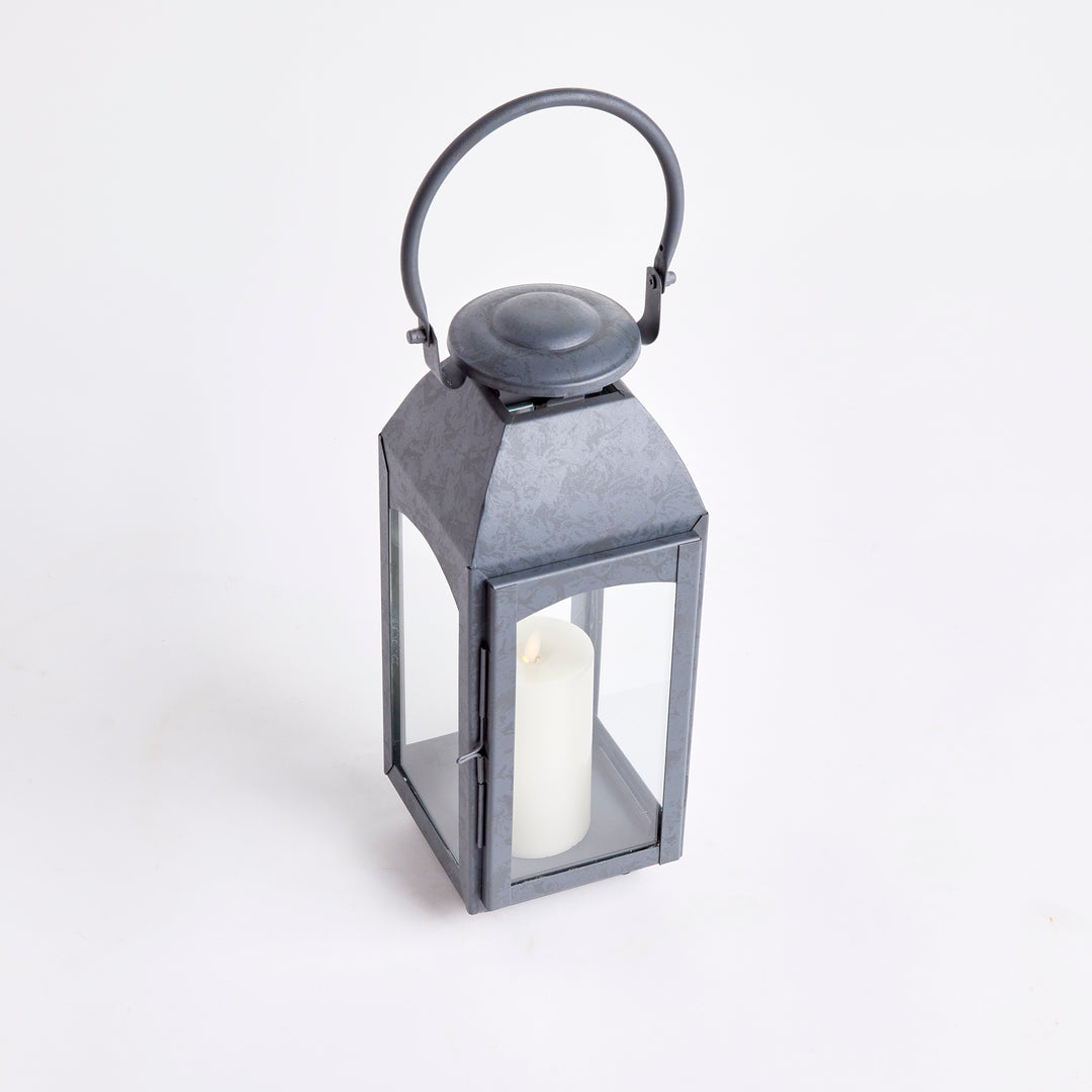 Crafted with a chic faux zinc finish and soft grey tone, this outdoor lantern brings a touch of old European style to your outdoor space. Its vintage-inspired design is true to the authentic qualities of the lantern, perfect for creating a sophisticated ambiance. Enhance your outdoor decor with the Antoinne Outdoor Gray Lantern Small and add a charming European touch.