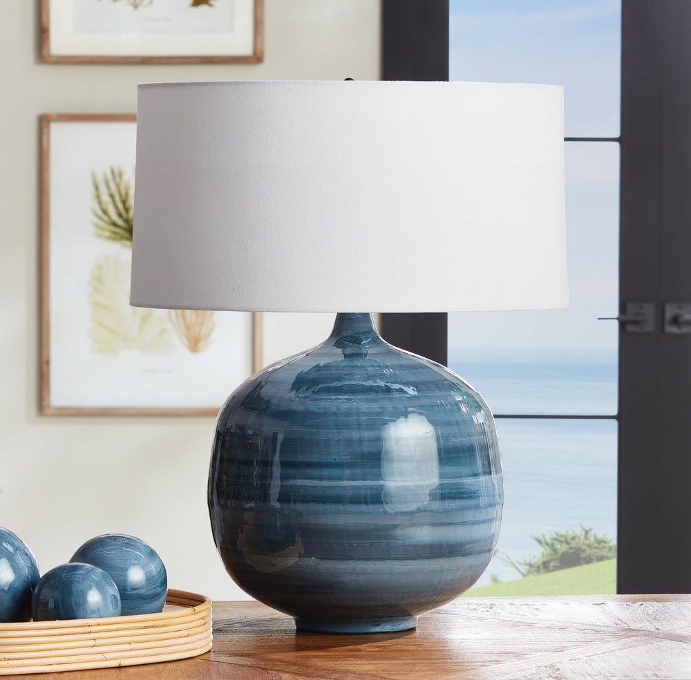 This blue table lamp features a unique design made of enameled iron and hand-painted for a lightweight yet elegant look. The horizontal swirl design adds a touch of refinement, while the oversized linen shade completes the modern aesthetic. A perfect addition to any contemporary living or dining space.