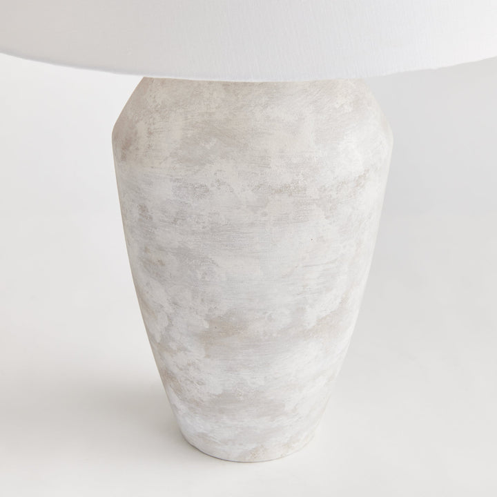 This elegant gray stone colored table lamp features a timeless shape, crafted from a wooden mold with centuries of history. Revamped with a cozy stone finish, it is completed with a tapered fabric shade making it a dynamic and intriguing addition to any family room, study, or bedroom