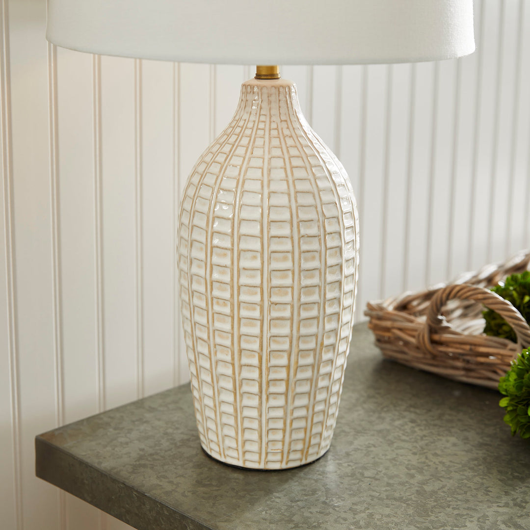 With a pressed pattern on the ceramic body, the Nadia Lamp is a work of art. Topped off with a generously scaled fabric shade, it is sure to enhance any space. intricate details, bold, finial, classic white, metal accents This ceramic lamp boasts an eye-catching pressed pattern and an elegantly designed fabric shade, making it an artistic addition to any room. With intricate details, a bold finial, and classic white coloring with metal accents, it offers both style and subtlety.