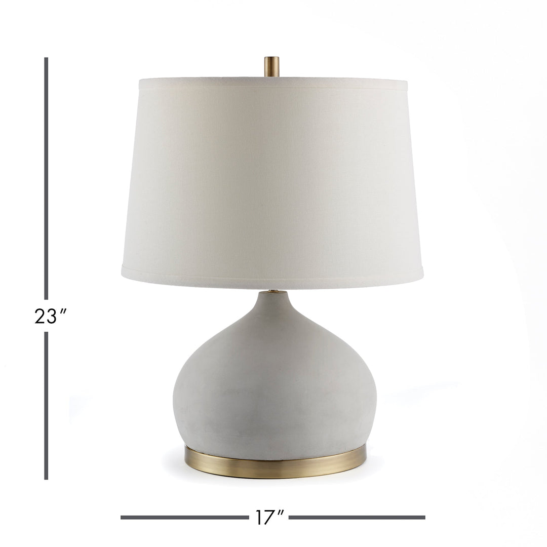 Constructed with both function and fashion in mind, the Suki lamp is a one-of-a-kind fixture that combines cement and brass accents. Its curvy base and wide shade make for distinctive details that add personality and style to any room. Crafted from premium ceramic with a concrete finish and complemented by antique brass accents, this lamp not only stands out but also ensures lasting durability for years of enjoyment. Dimensions