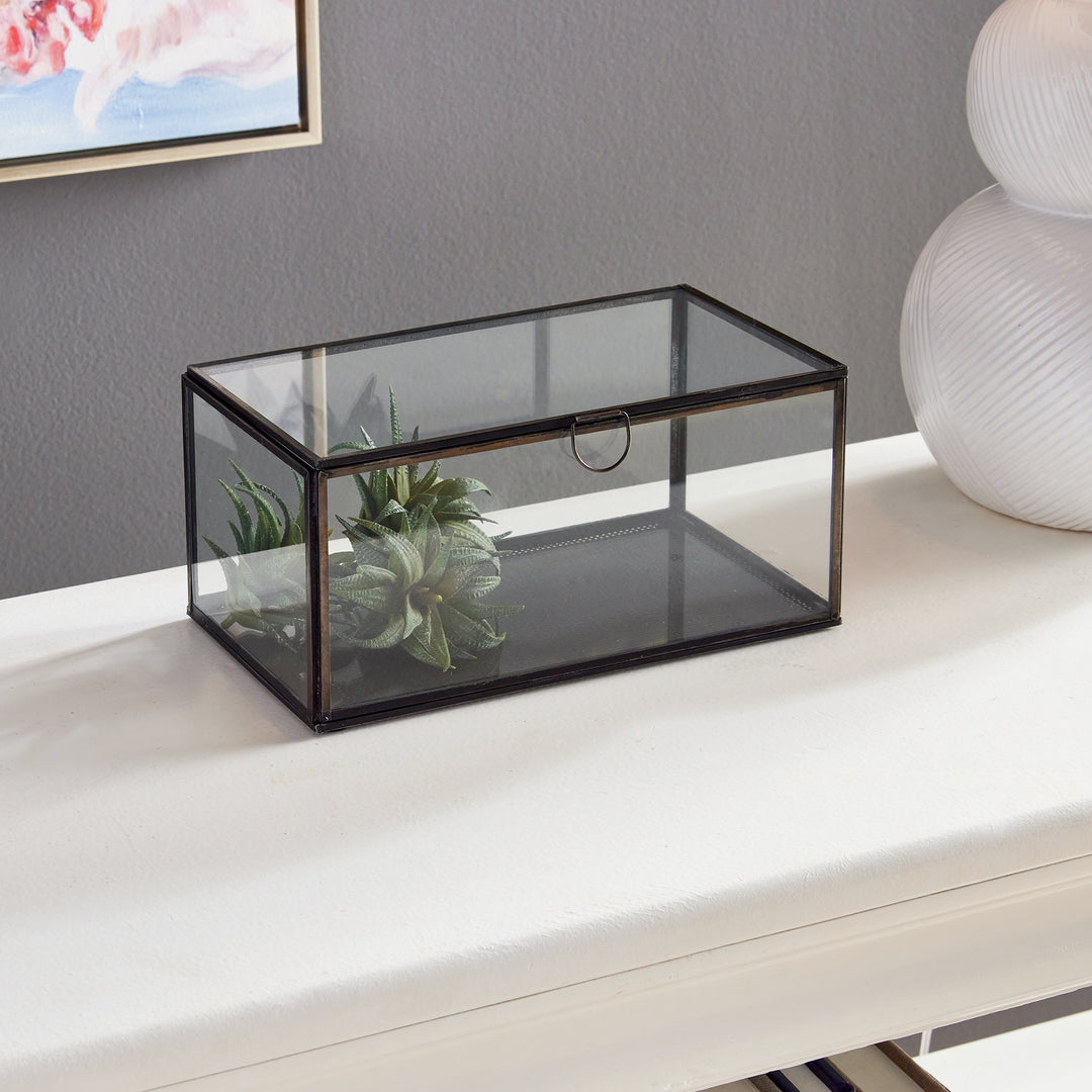 The Arwen Rectangular Black Display Box is the ideal solution for elegantly displaying and preserving your valuable keepsakes. Made of glass and brass with a delicate loop handle, this carefully crafted box ensures your mementos remain in pristine condition while adding a touch of style to your décor. By investing in this display box, you can showcase your most treasured items with ease and sophistication.