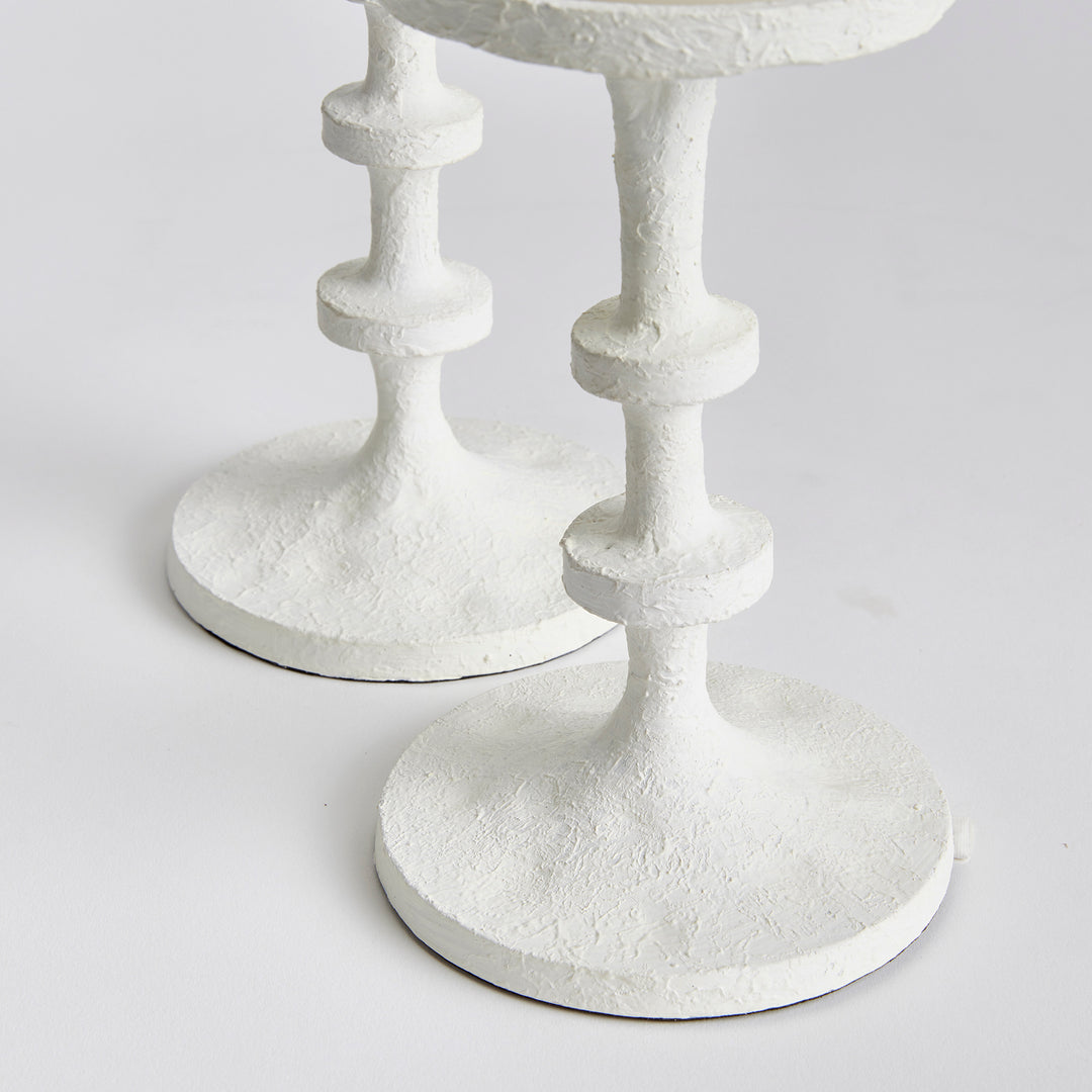 These candle stands feature notches along the body, reminiscent of the traditional method of counting, adding a playful touch. They are designed to hold up to 4" diameter pillars and are ideal for display on a mantle or at the front entry. Not only do they add a charming reference to traditional counting, but they also bring a modern element to the space. With a capacity of up to 4" diameter pillars, this set of two stands is a practical and stylish addition to any mantle or front entryway.