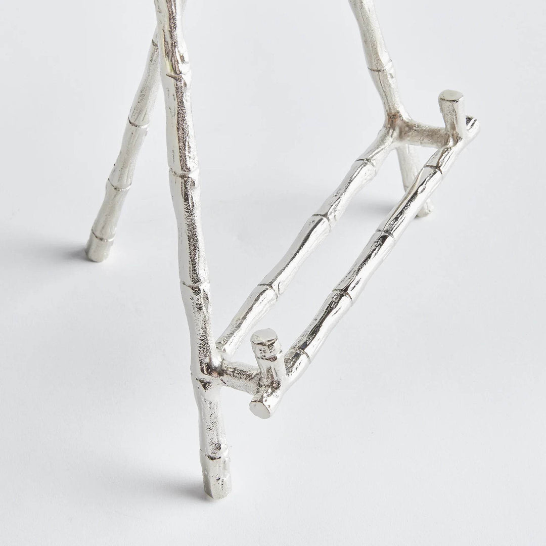 Elevate your decor with this sturdy and resilient silver easel, expertly crafted to exhibit platters, cookbooks, or small art pieces. The traditional aesthetic of bamboo-like silver details adds a timeless charm, while the versatile design allows for effortless display of various items.